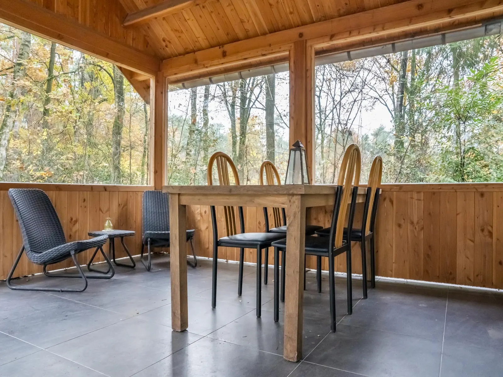 The veranda up close: table for six, lantern, autumn woods all round