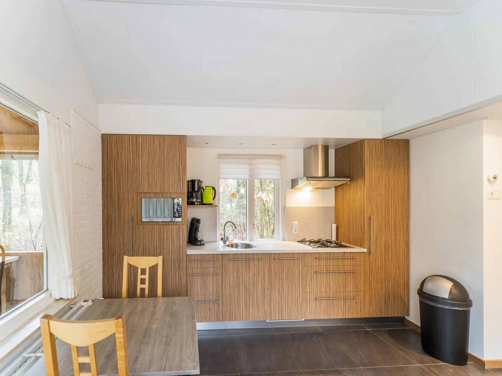 Kitchen with wood fronts, gas hob and dining table by the window