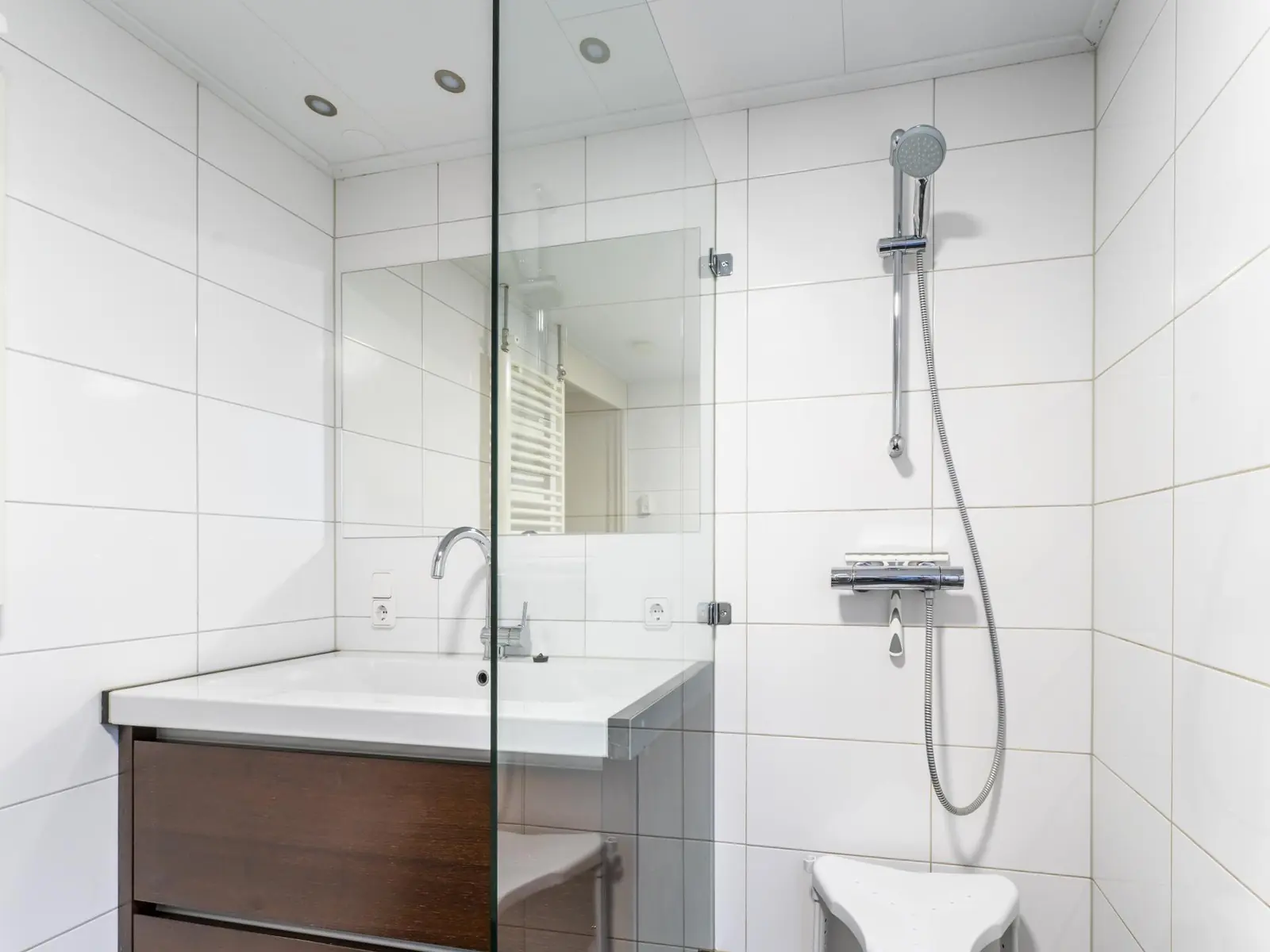 Bathroom: washbasin and walk-in shower behind glass