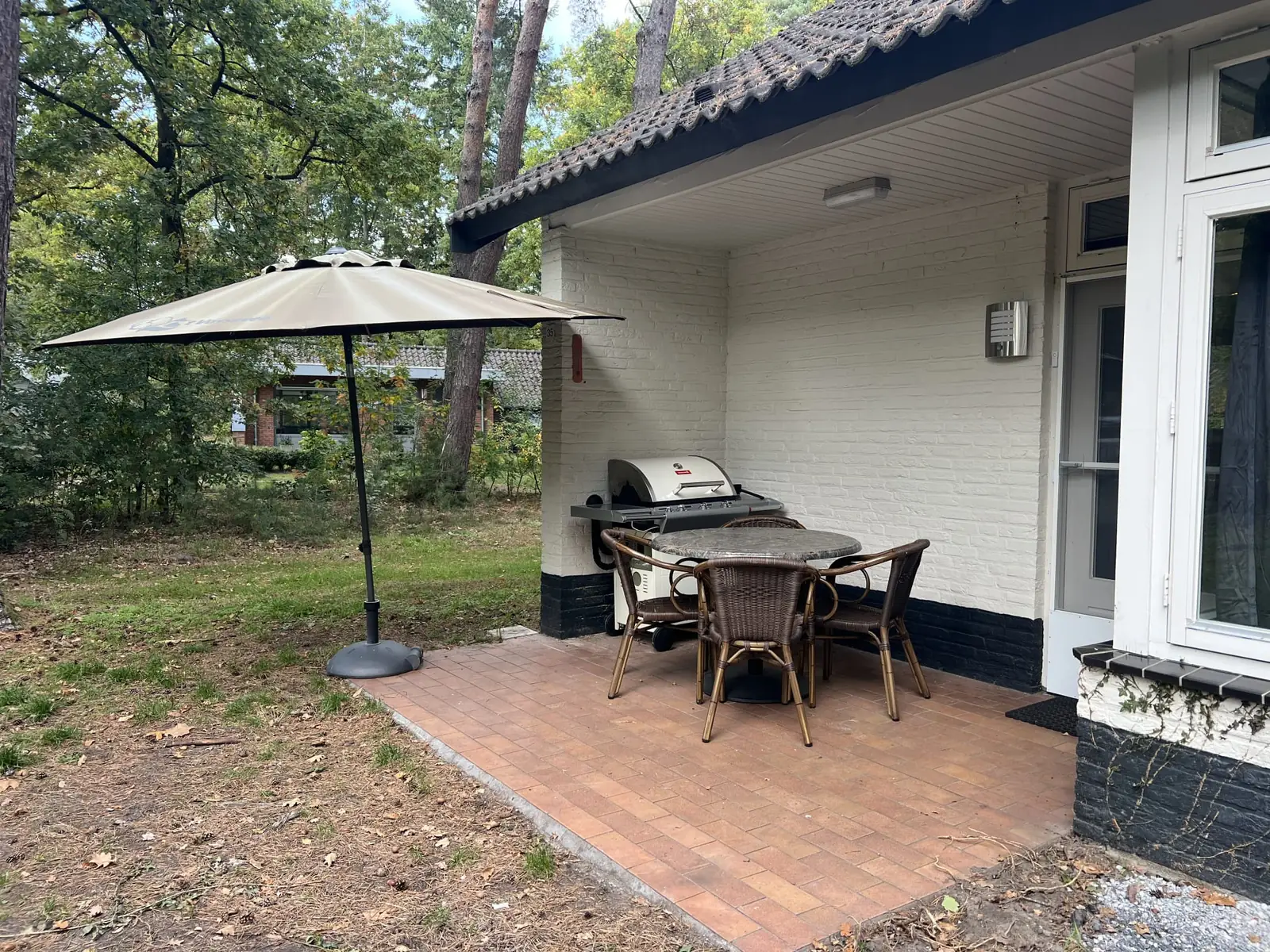 The covered terrace with gas barbecue, table and parasol