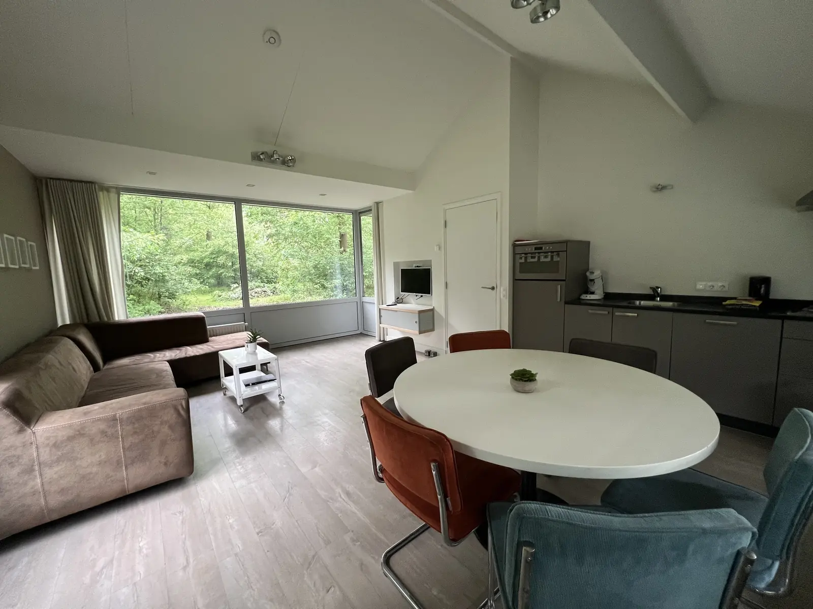 Seating area, dining table and kitchen in one room under the sloping roof