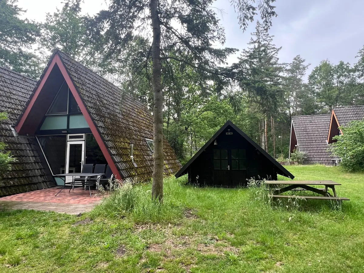 The A-frame among the trees, with the terrace, table and chairs