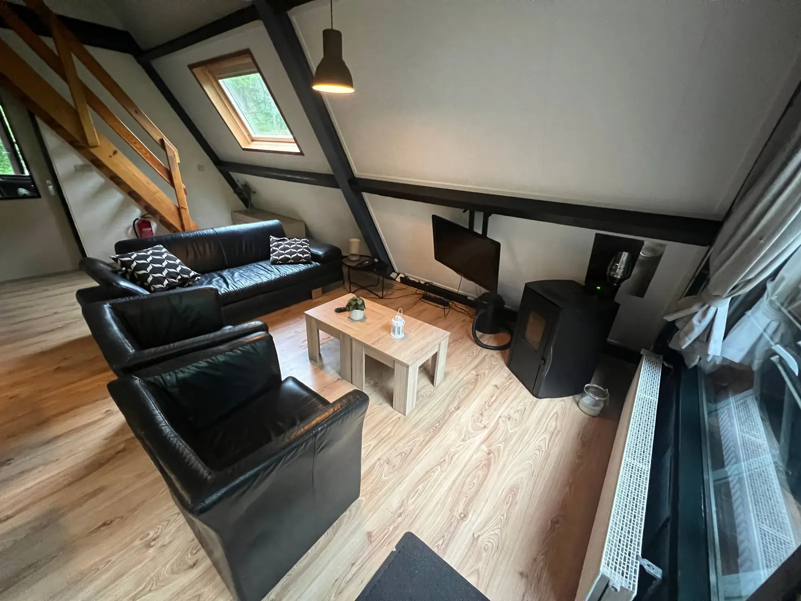 Seating area with a black leather sofa and armchairs, two coffee tables and a stove
