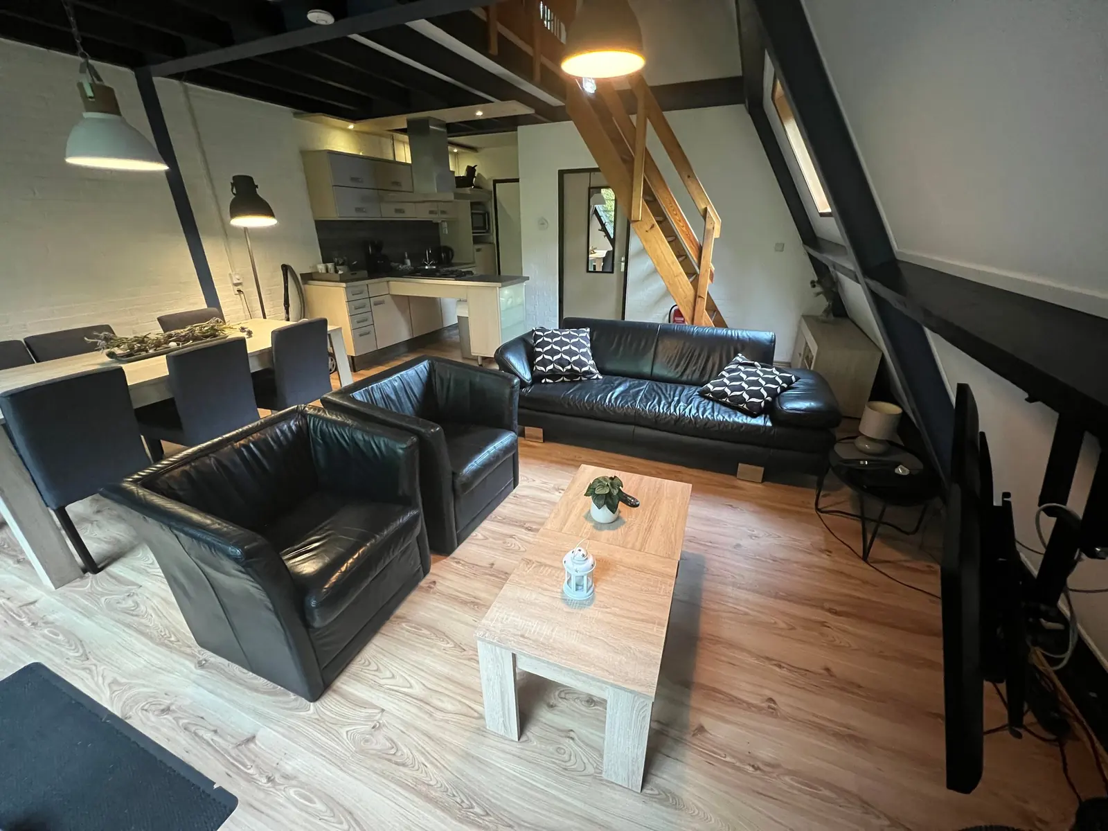 Seating area, dining table and kitchen in one space, with the open wooden staircase to the upper floor
