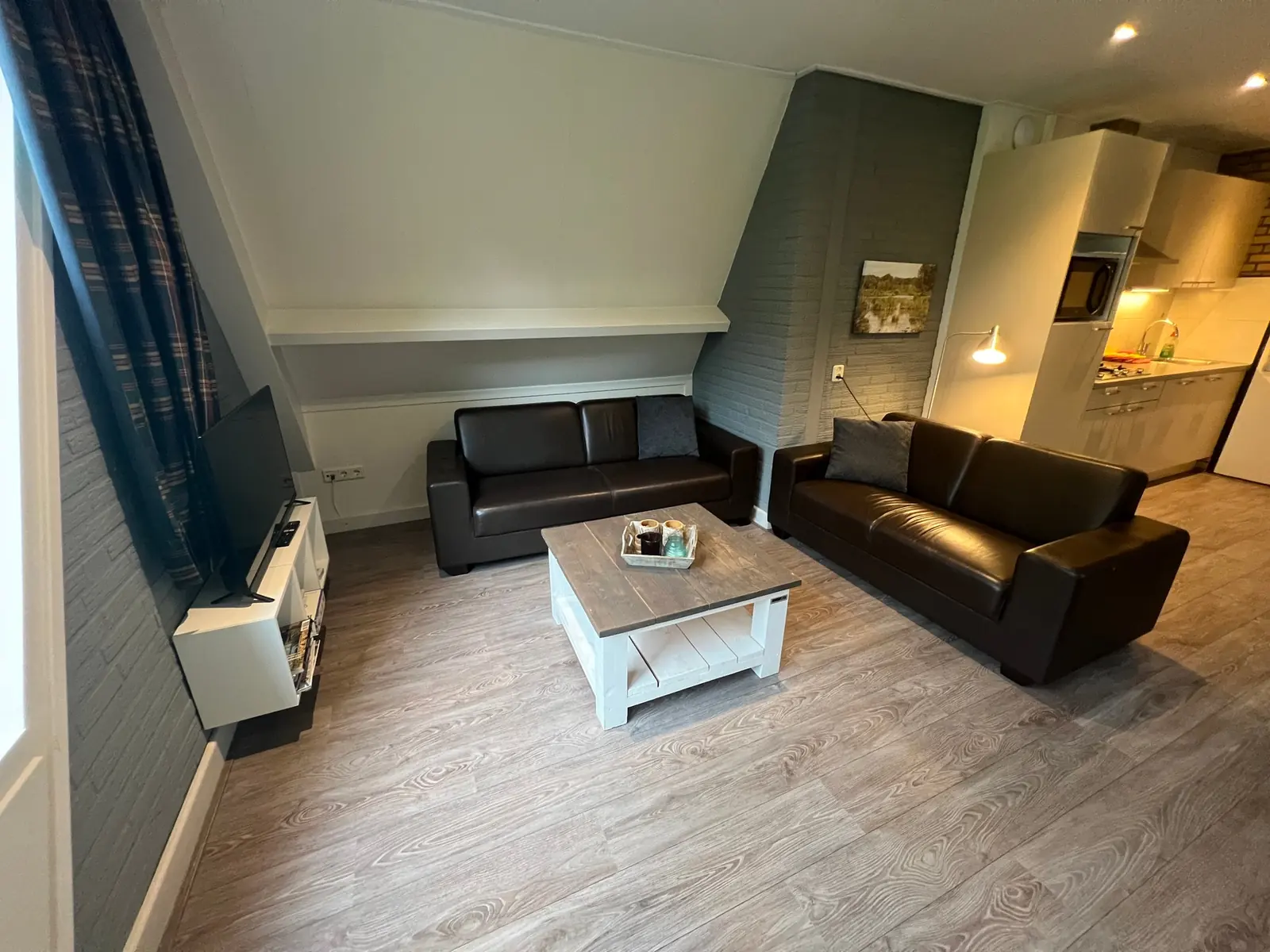Seating area with two brown leather sofas, a coffee table and TV