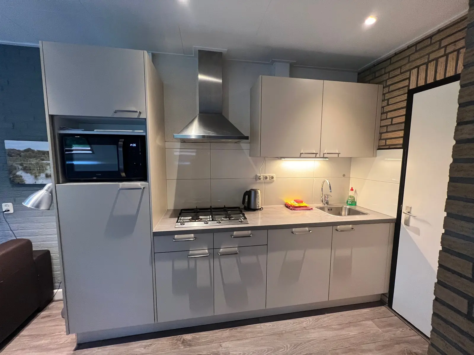 Kitchen with gas hob, extractor hood, microwave and sink