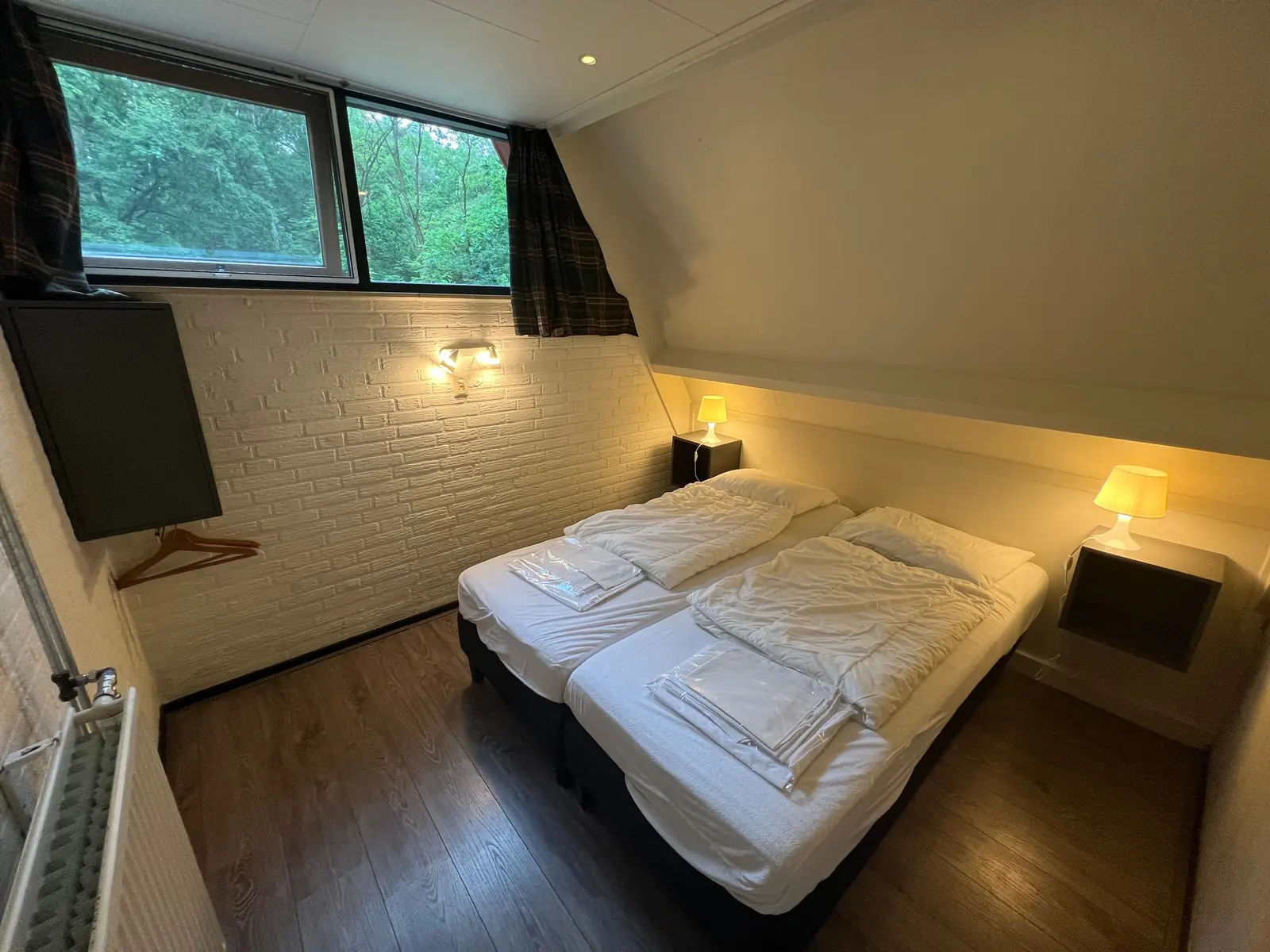 Bedroom with two single beds pushed together and a wide window