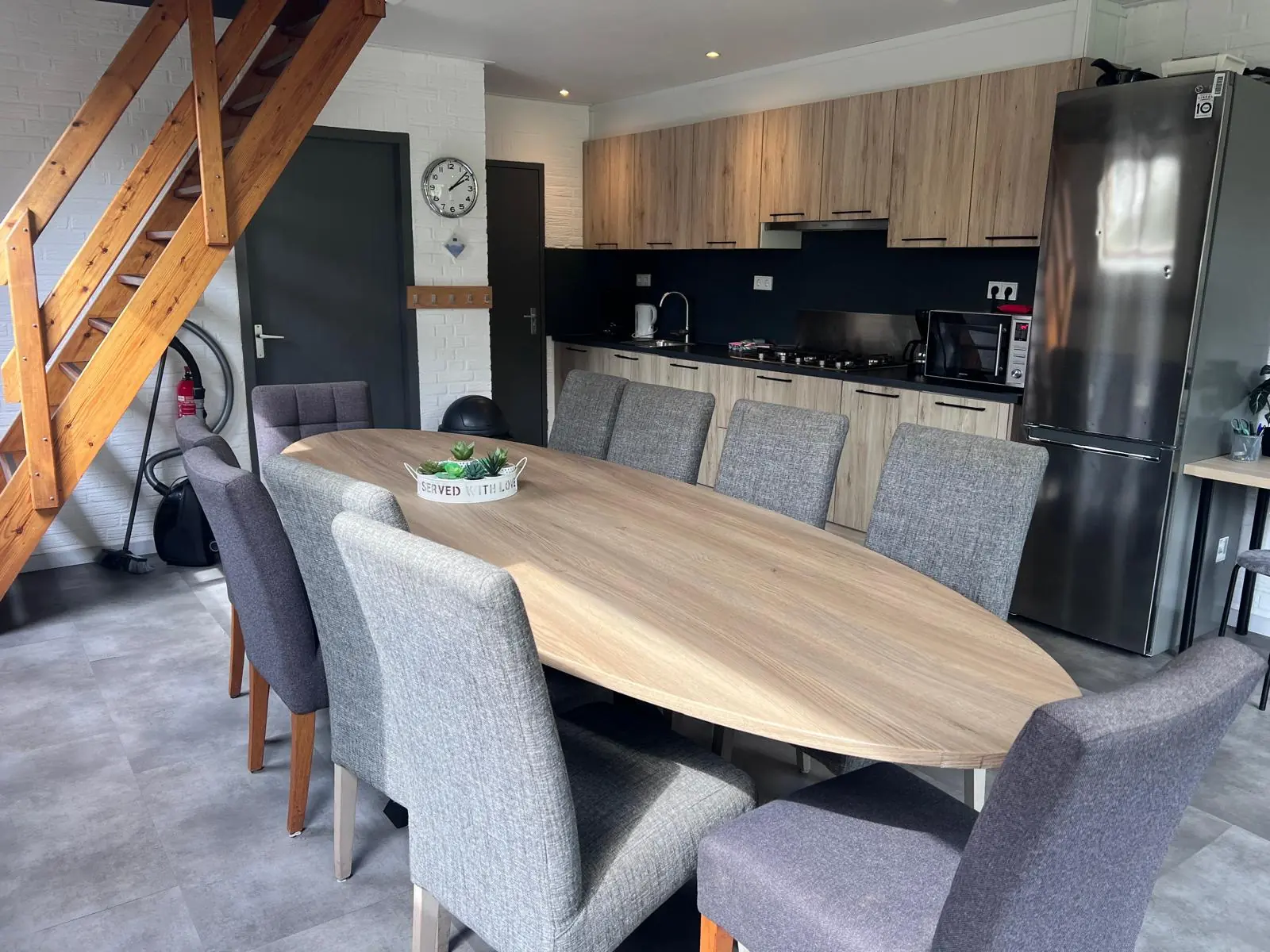 Oval dining table with chairs, the open stair and the kitchen behind