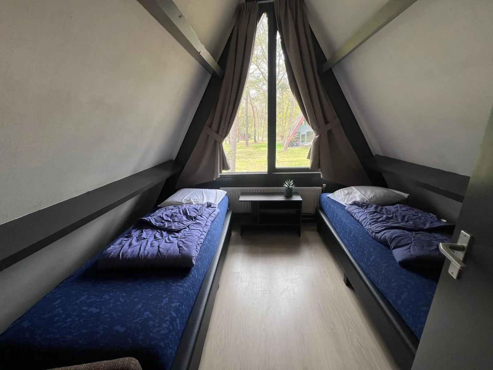 Bedroom in the apex of the A-frame, with the triangular window