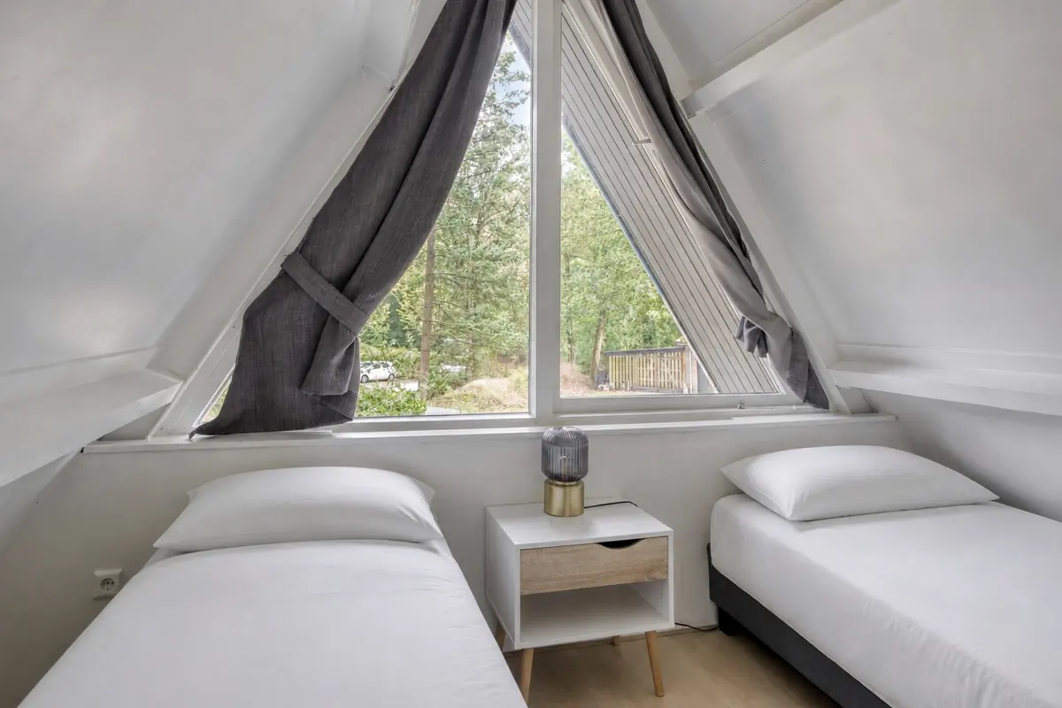 Slaapkamer boven met twee bedden en het driehoekige raam