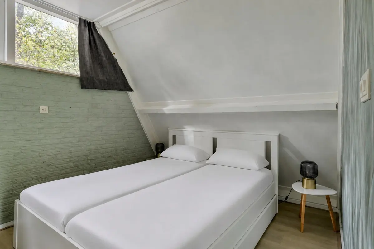 Slaapkamer met twee bedden tegen elkaar onder de schuine wand