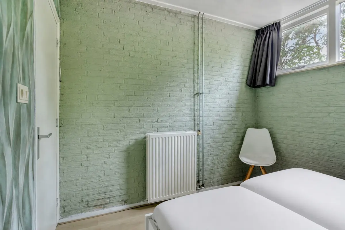 Slaapkamer met groen geschilderde bakstenen wand