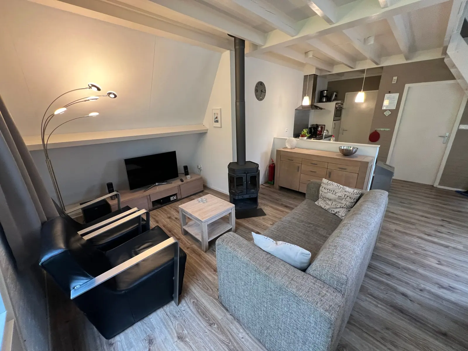 Seating area with a grey sofa, two leather armchairs, TV and a stove